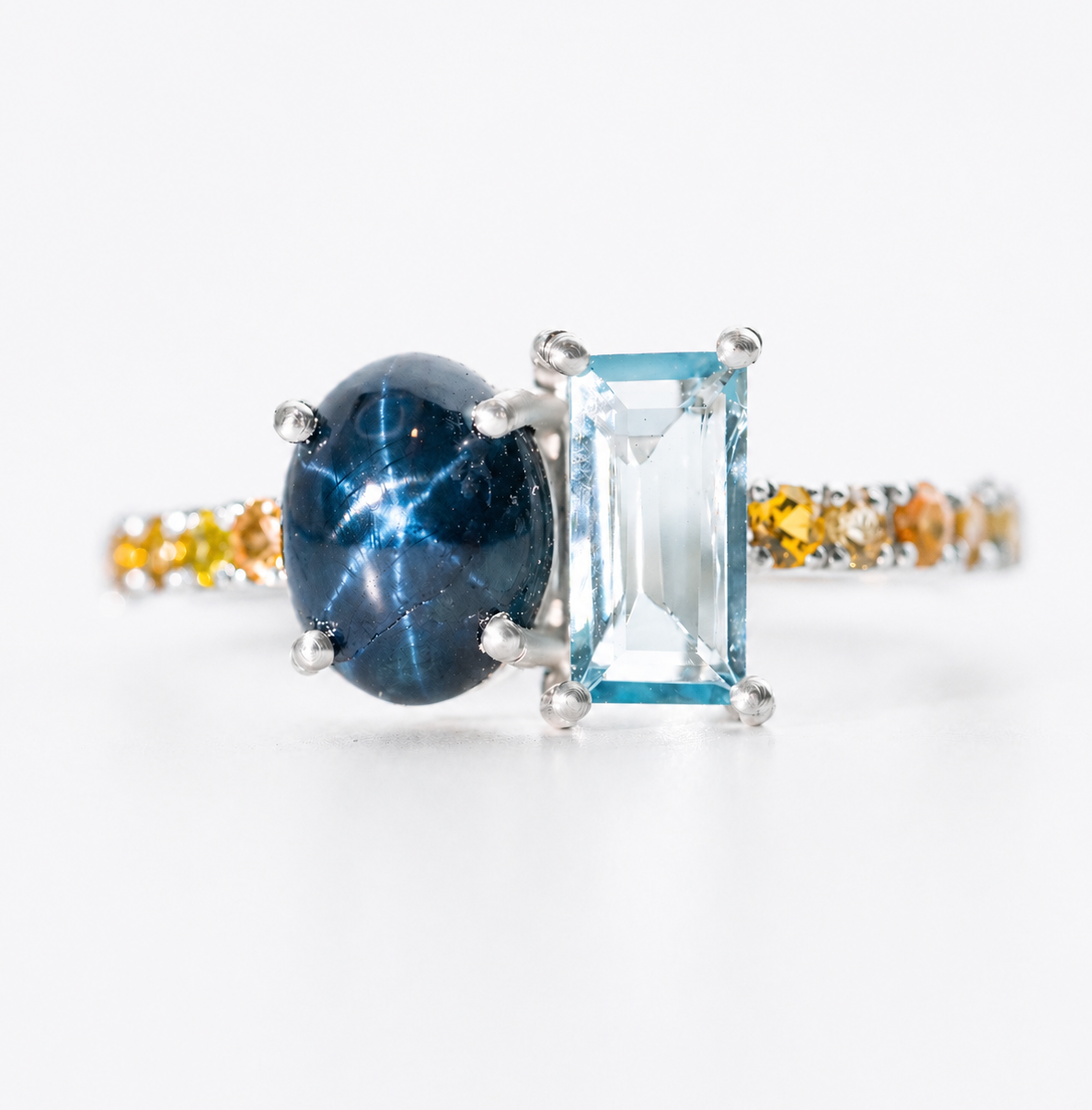 Anillo Ámara de plata 925 con zafiro azul estrella, aguamarina talla esmeralda y zafiros amarillos sobre fondo neutro